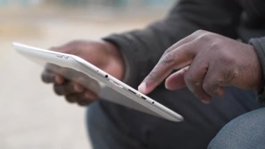Afrikalı Amerikalı adam tablet bilgisayar kullanıyor. Siyah adamın elleri bir tablet bilgisayar tutuyor, yakın çekim. Tablet bilgisayarlı Afrikalı çalışmalar, sosyal ağlarda görüntülere göz atıyor