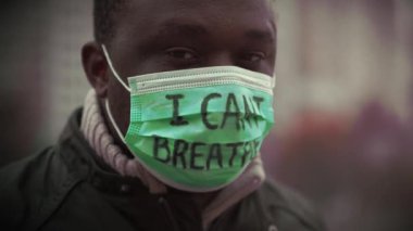 Tıbbi maskeli Afrikalı Amerikalı bir eylemci. Üstünde 