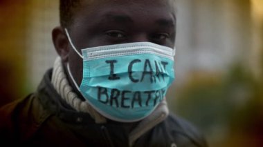 Tıbbi maskeli Afrikalı Amerikalı bir eylemci. Üstünde 
