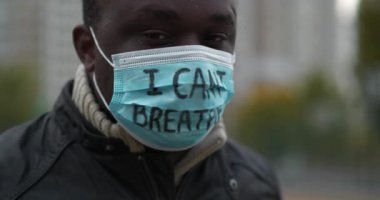 Tıbbi maskeli Afrikalı Amerikalı aktivistin eğik bir görüntüsü var. Üzerinde 