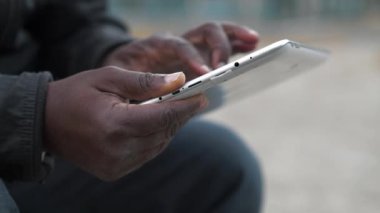 Slow Motion Afrikalı Amerikalı adam tablet bilgisayar kullanıyor. Siyah adamın elleri tablet bilgisayarı tutuyor, kapat. Tablet bilgisayarlı Afrikalı çalışmalar, sosyal ağlarda yayınlar