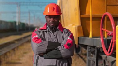 Yük treni terminalindeki Afrikalı Amerikalı demiryolu işçisi. Demiryolu işçisi üniformalı ve kırmızı şapkalı, kameraya bak.