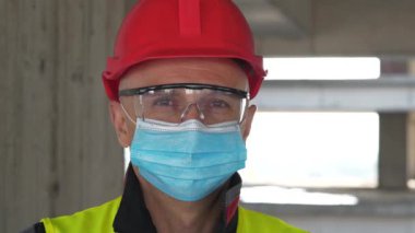 Mavi tıbbi koruyucu maskeli, gözlüklü ve kırmızı şapkalı işçiler kameraya bakıyor. Covid konsept sağlık ve güvenlik, koronavirüs karantinası, sosyal uzaklık, bir sonraki dalga covid virüs koruması