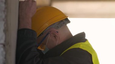 Slow Motion Stresli İşçi inşaat alanında duruyor ve ellerini ve kafasını duvara vuruyor, kendini kınama, kendine işkence, endüstriyel kaza