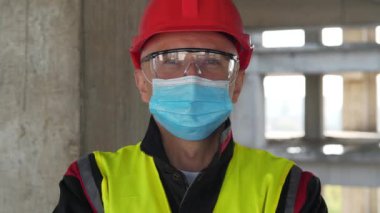 Tıbbi koruyucu maskeli, gözlüklü ve kırmızı başlıklı adam kameraya bakıyor. Covid konsept sağlık ve güvenlik, koronavirüs karantinası, sosyal uzaklık, bir sonraki dalga covid virüs koruması