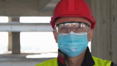 Tıbbi koruyucu maskeli ve gözlüklü işçiler kameraya bakar. Alnında kırmızı lazer ışını yükselir ve parlar. Covid konsept sağlık ve güvenlik, sonraki dalga covid virüs koruması