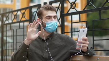 Ağır çekim maskeli adam kürsüde oturuyor ve akıllı telefon aracılığıyla iletişim kuruyor, gülümsüyor ve keyfi yerinde. Sonra maskesini çıkardı ve onsuz konuşmaya devam etti.