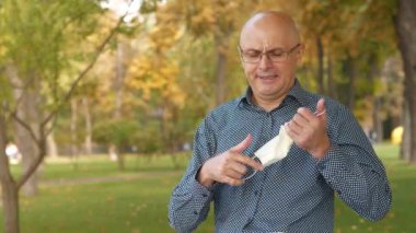 Slow Motion Kel Gözlüklü yaşlı adam maskeyi çıkardı, düzeltti, maskeyi tekrar taktı ve eline bir tablet bilgisayar aldı.
