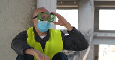 İşçi şapkasını, gözlüklerini, tıbbi koruyucu maskesini çıkardı ve derin bir nefes aldı, özgürce nefes aldı. Sinema 4K 60fps video