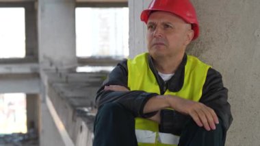 Kırmızı başlıklı işçi inşaat alanında oturur, sonra mavi tıbbi koruyucu maske takar. 4K 60fps eğik video