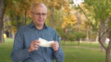 Gözlüklü yaşlı adam maskesini çıkardı, tekrar maskeyi taktı ve eline bir tablet bilgisayar aldı.
