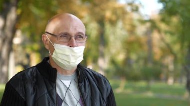 Gözlüklü ve tıbbi koruyucu maskeli kıdemli adam fındık yiyor.