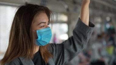 Tıbbi koruyucu maskeli kız metro vagonunda duruyor.