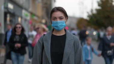 Kalabalık caddede tıbbi koruyucu maskeli genç bir kadın. Covid konsept sağlık ve güvenlik, N1H1 koronavirüs karantinası, bir sonraki dalga covid virüs koruması. Zamanı Geri Alma Yavaş Hareket videosu
