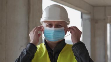 Slow Motion Workman inşaat alanında kasketli, koruyucu maske takıyor ve sana bakıyor.