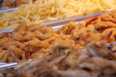 Fast food restoranında kaynatılmış, kızartılmış ve bol yağda kızartılmış çeşitli yemekler. Çeşitli şekillerde pişirilmiş patatesler. Patates kızartması, kızarmış patates.