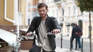 Mutlu genç adam sokakta bisiklete biner ve gülümser. Sırt çantalı bisikletli kurye, keyfi yerinde, gülümsüyor ve hayattan zevk alıyor, mutlu, gidonu dönüyor ve seyahat hayalleri kuruyor.