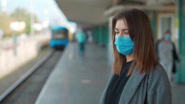 Tıbbi maskeli kadın metro istasyonunda duruyor.