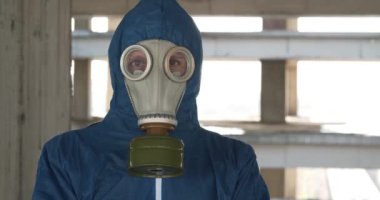 Gaz maskesi ve kimyasal koruma giysisi giyen işçiler kameraya bakıyor. Endüstriyel bölgede maskeli bir adam. Sinema 4K 60fps video