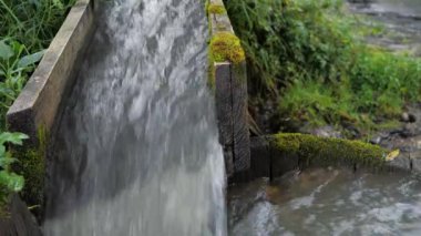 Yavaş hareket eden su, ahşap bir olukta akıyor.