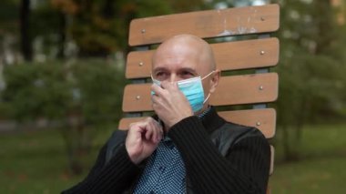 Kel adam tıbbi koruyucu maske takar, gözlük takar ve eline bir tablet bilgisayar alır.