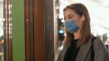 Restorana girmeden önce vücut ısısını ölçmek. Tıbbi koruyucu maskeli genç bir kadın kahve dükkanına giriyor. Covid-19 koronavirüs semptomları için insanların taranması