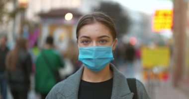 Sinema 4K 60fps Kalabalık bir sokakta koruyucu maske takan genç bir kadın. Covid konsept sağlık ve güvenlik, N1H1 koronavirüs karantinası, ikinci dalga covid virüs koruması