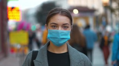 Kalabalık bir caddede, Zaman Yavaşlığı Hareketi 'ndeki tıbbi koruyucu maskeli genç kadın. Covid konsept sağlık ve güvenlik, N1H1 koronavirüs karantinası, ikinci dalga covid virüs koruması