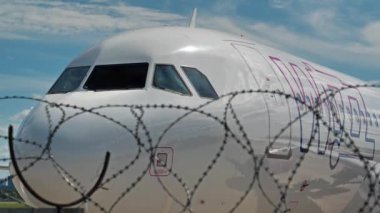 UKRAINE, KYIV, 21 Temmuz 2020: Covid-19 salgını sırasında çalışmayan, Igor Sikorsky Kyiv Uluslararası Havalimanı 'nda duran Wizz Air uçağının dikenli telleriyle çitin arkasından bakın.