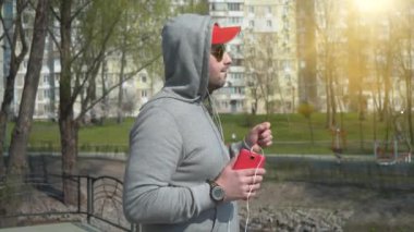 Kırmızı şapkalı ve güneş gözlüklü adam müzik dinler ve dans eder.