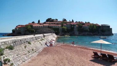 SVETİ STEFAN, MONTENEGRO, 30 Haziran 2019: Sveti veya Saint Stefan 'daki plajdaki insanlar - Adriyatik kıyısındaki tatil ve küçük ada, Budva Riviera