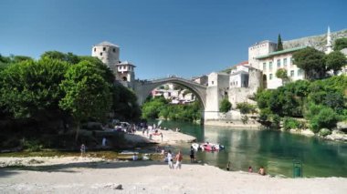 MOSTAR, BOSNIA VE HERZEGOVINA, 2 Temmuz 2019: Bosna-Hersek Federasyonu Federasyonu Neretva Kantonu 'nun şehir ve idari merkezi Mostar' daki Neretva Nehri yakınlarındaki insanlar