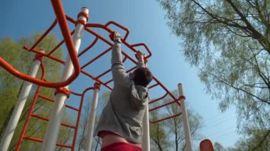 Sporcu yorucu bir egzersiz yapıyor. Adam spor sahasında fiziksel egzersiz yapıyor. Açık hava spor salonunda gözlüklü adam egzersizi yapıyor.