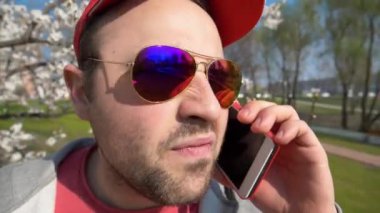 Çok kızgın bir adam telefona bağırıyor. Gözlüklü sinirli adam akıllı telefondan konuşuyor. Kırmızı akıllı telefonlu traşsız duygusal adam. Yaklaş.