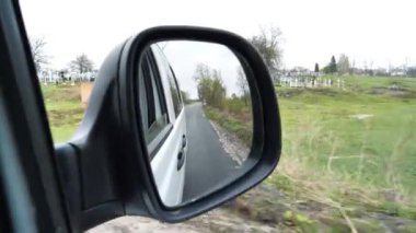 Araba mezarlık boyunca gidiyor. Arabanın yan aynasına bak.