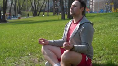 Sporcu çimenlerde oturup antrenmandan önce meditasyon yapıyor. Adam şehir parkında meditasyon yapıyor. Meditasyon - bireyin zihni çalıştırdığı, eğittiği ya da bir bilinç biçimini tetiklediği uygulama