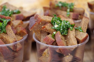 Plastik bardakta küçük ekmek parçaları. Kızarmış tuzlu ekmek ve yeşil soğan, tereyağı ve sarımsak.