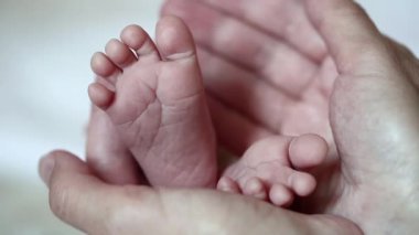 Küçük bebek ayaklı annenin elleri. Bir aylık erkek bebek. Annem küçük bebek ayaklarını elinde tutuyor.