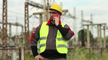Elektrik santralindeki işçiler akıllı telefondan konuşur. Elektrik santralinde cep telefonuyla çalışan bir elektrik mühendisi.