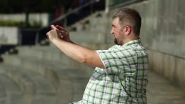 İş adamı oturur ve akıllı telefondan video kaydeder. Şişman adam cep telefonuyla fotoğraf çekiyor.