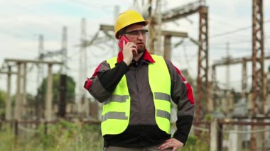 Elektrik santralindeki işçiler akıllı telefondan konuşur. Elektrik santralinde cep telefonuyla çalışan bir elektrik mühendisi.