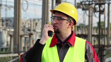 Isı santralindeki işçiler radyo istasyonuyla iletişim kuruyor. Elektrik santralinde taşınabilir radyo vericisi olan bir işçi.