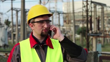 Elektrik santralindeki işçiler akıllı telefondan konuşur. Elektrik santralinde cep telefonuyla çalışan bir elektrik mühendisi.