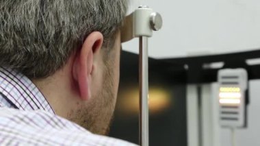 Dinamik fototerapi için bir cihaz. Optalmoloji kliniğindeki hasta, adam göz doktoru odasındaki dinamik fototerapi cihazına bakıyor, ışık tedavisi görüyor.