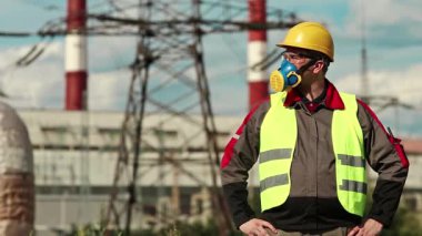 Sanayi bölgesinde baret, gözlük ve solunum cihazı takan tamirci. Elektrik santralinde kimyasal koruması olan bir işçi.