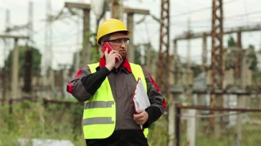 Elektrik santralinde cep telefonuyla çalışan bir elektrik mühendisi. Elektrik santralindeki işçiler akıllı telefondan konuşuyor