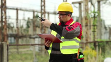 Isı santrali enerji mühendisliği uzmanı radyo istasyonu aracılığıyla iletişim kuruyor. Elektrik santralinde taşınabilir radyo vericisi olan elektrikçi.