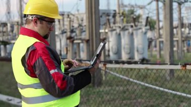 Elektrik santralinde bilgisayarı olan bir elektrikçi. Elektrik santralinde baret takan bir işçi, mühendislik denetimi. Tablet bilgisayarlı fabrika işçisi