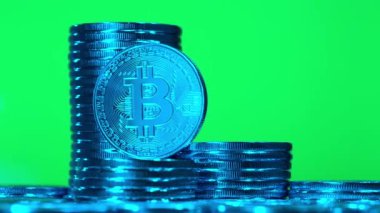 Bitcoin 'ler yeşil arka planda mavi ışıkta. Kripto para birimi Altın Bitcoin, BTC, Bit Coin, Blockchain teknolojisi, bitcoin madencilik konsepti, yeşil arka planda dönen makro mavi bitcoin vuruşu