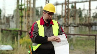 Elektrik santralinde çalışan bir işçi. Elektrik santralinde inşaat belgeleriyle çalışan bir güç adamı. Tasarım çizimleri olan sert şapkalı ana mimar.